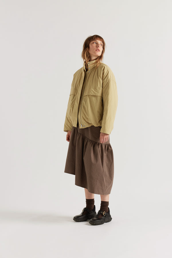 Front of female model in the Sand Beige Surge Quilted Jacket worn open, showing relaxed silhouette, military tab collar and storm flap pocket detailing