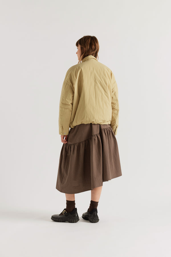 Back view of the sand beige Surge Quilted Jacket showing dropped shoulders, gently sculpted sleeves and relaxed quilted silhouette