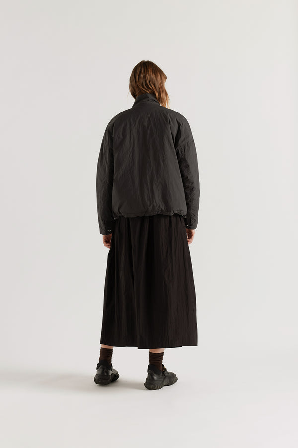Back view of the black Surge Quilted Jacket showing dropped shoulders, gently sculpted sleeves and relaxed quilted silhouette