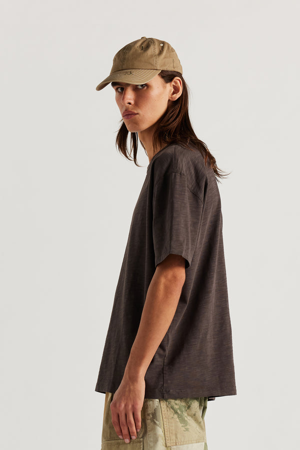Front view of female model wearing Unisex Ancient Language Cap in Pink, featuring all-over embroidered motifs inspired by Vinča markings